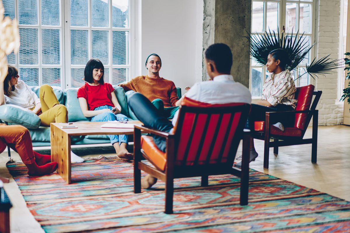 Group,of,multiracial,people,resting,on,comfortable,seats,around,table,co-living